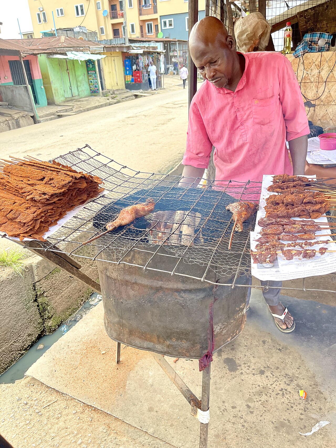 Suya vendor grilling spiced meat skewers in Nigeria